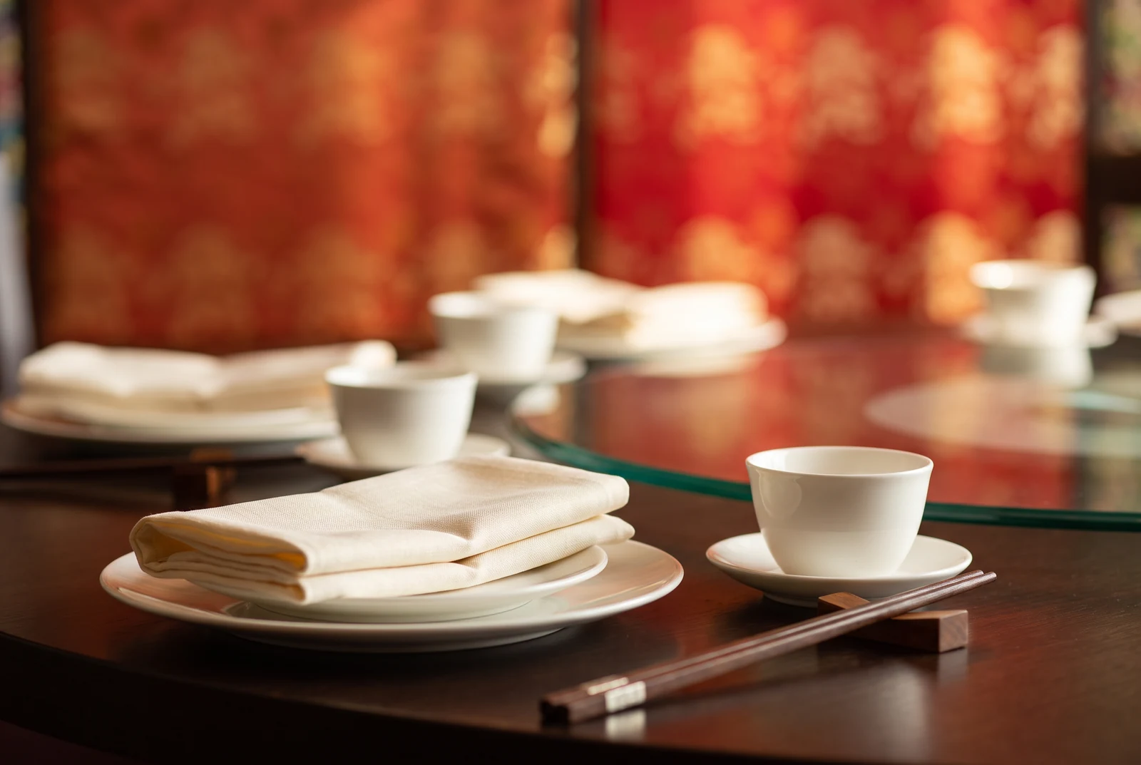 Folded linen napkin, white porcelain and dark chopsticks at a place setting